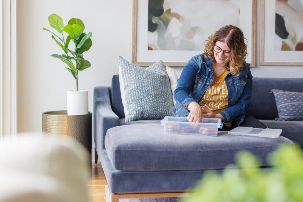 woman sitting on couch and smiling while sorting toys