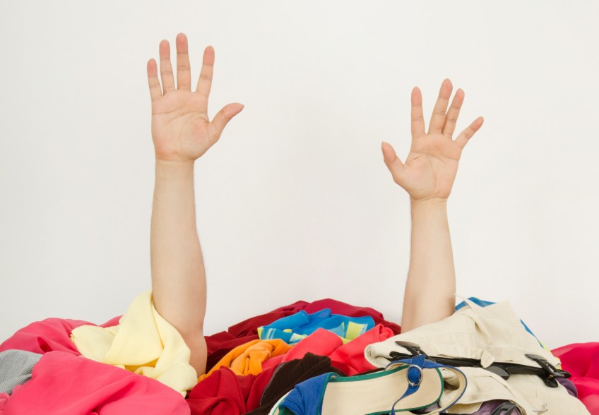 hands reaching out of a pile of clothing