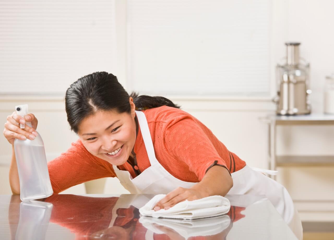 smiling woman cleaning kitchen counter