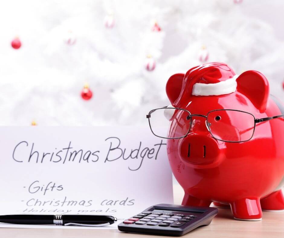 red piggy bank wearing a santa hat and glasses next to a calculator and christmas budget list