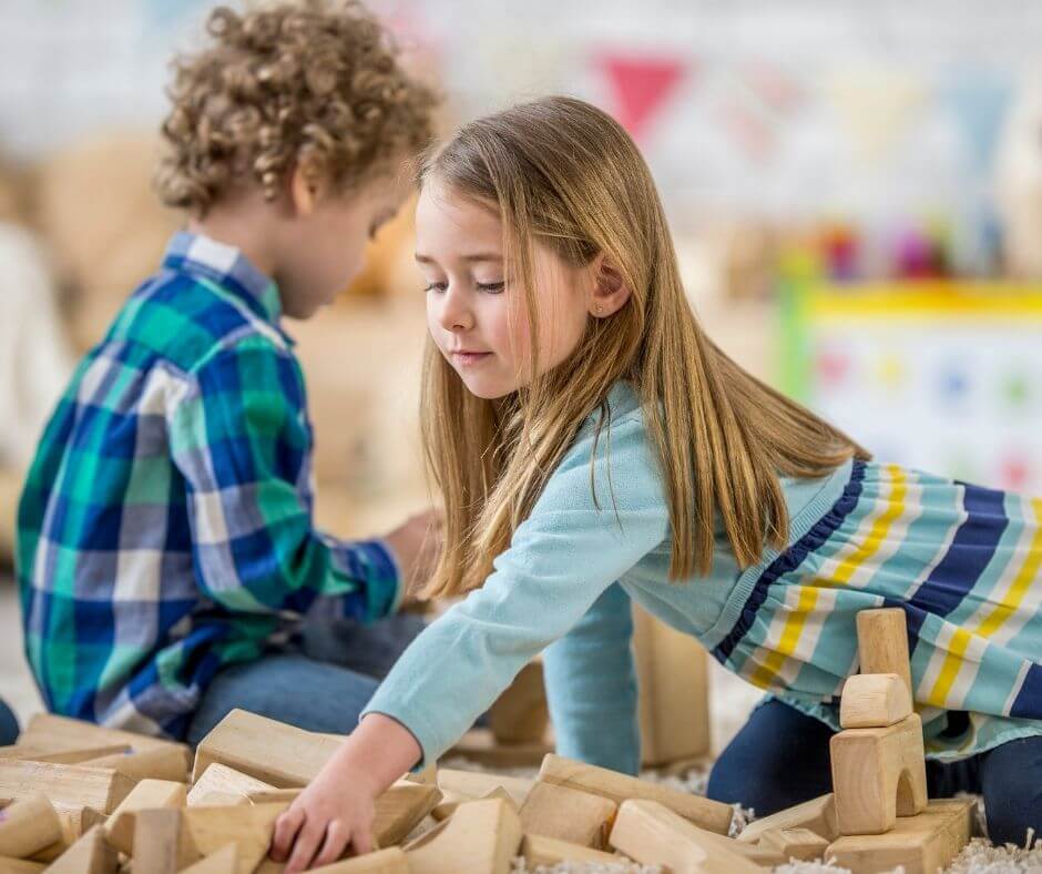 young boy and girl playing with naturl wooden blocks