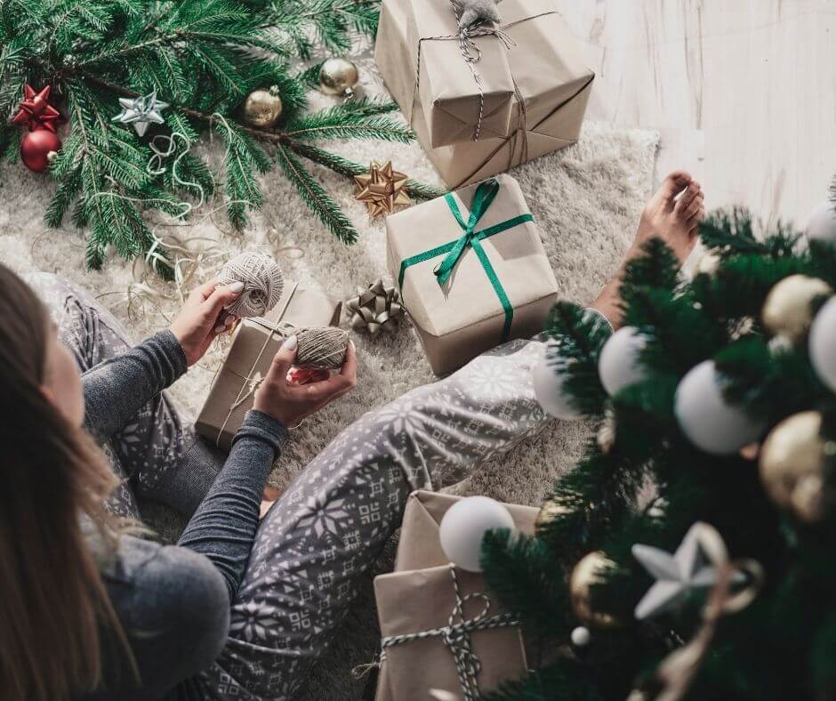 woman in pajamas wrapping christmas presents