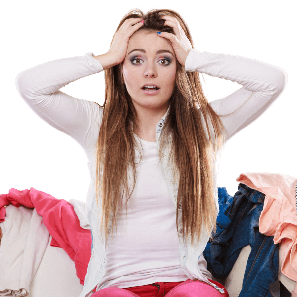 stressed woman sitting on couch surrounded by clothes