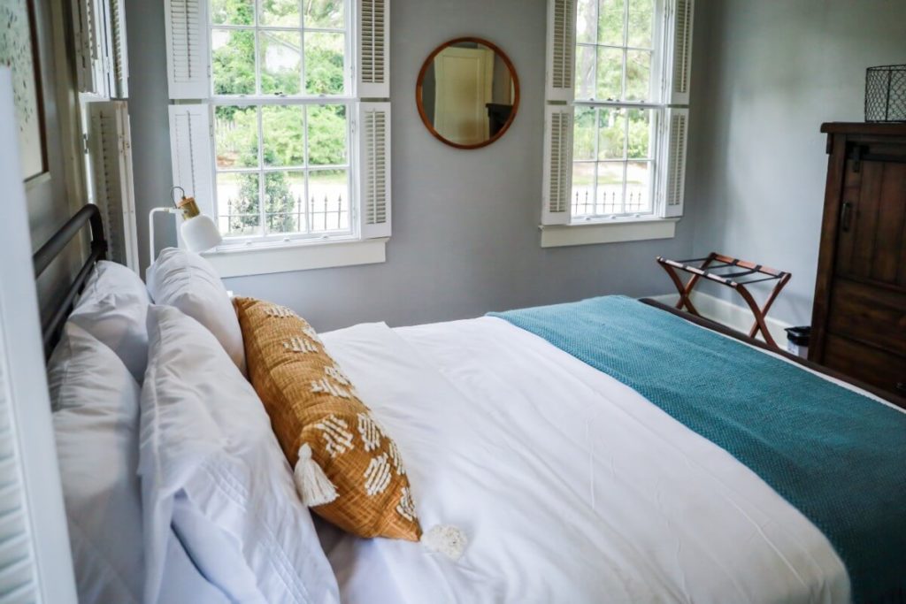 interior of guest bedroom in a short term rental with bed, armoire, mirror, and luggage rack