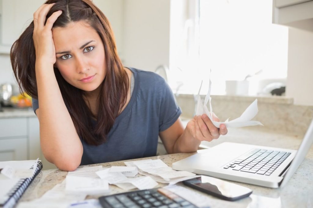 woman paying bills at kitchen counter
