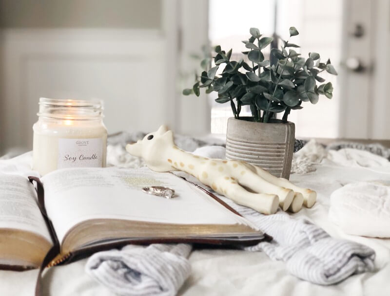 When Decluttering Hurts - A Photo of a lit candle, open bible, wedding rings, baby socks, and a baby teether arranged as a memorial.