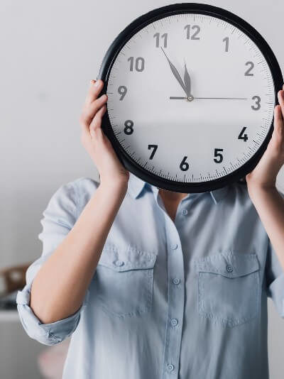woman holding clock in front of her face