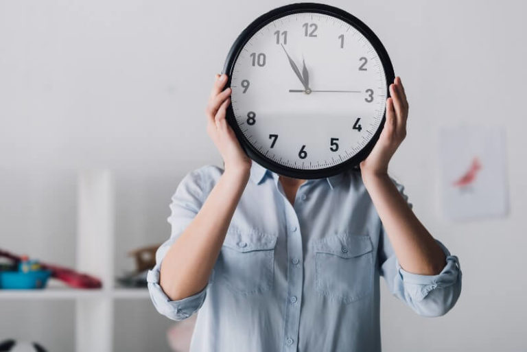 woman holding clock in front of her face