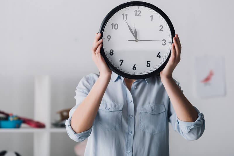 woman holding clock in front of her face