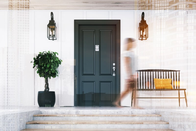 Blurry photo of woman walking past a black front door.