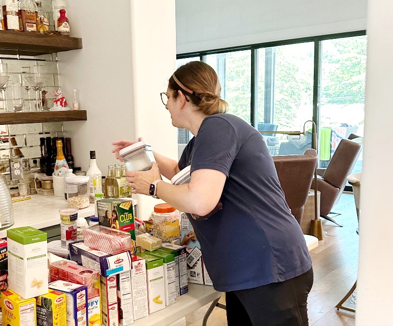 Professional organizer Andrea Brame of Nolensville Home Organizing sorting pantry items next to a bar
